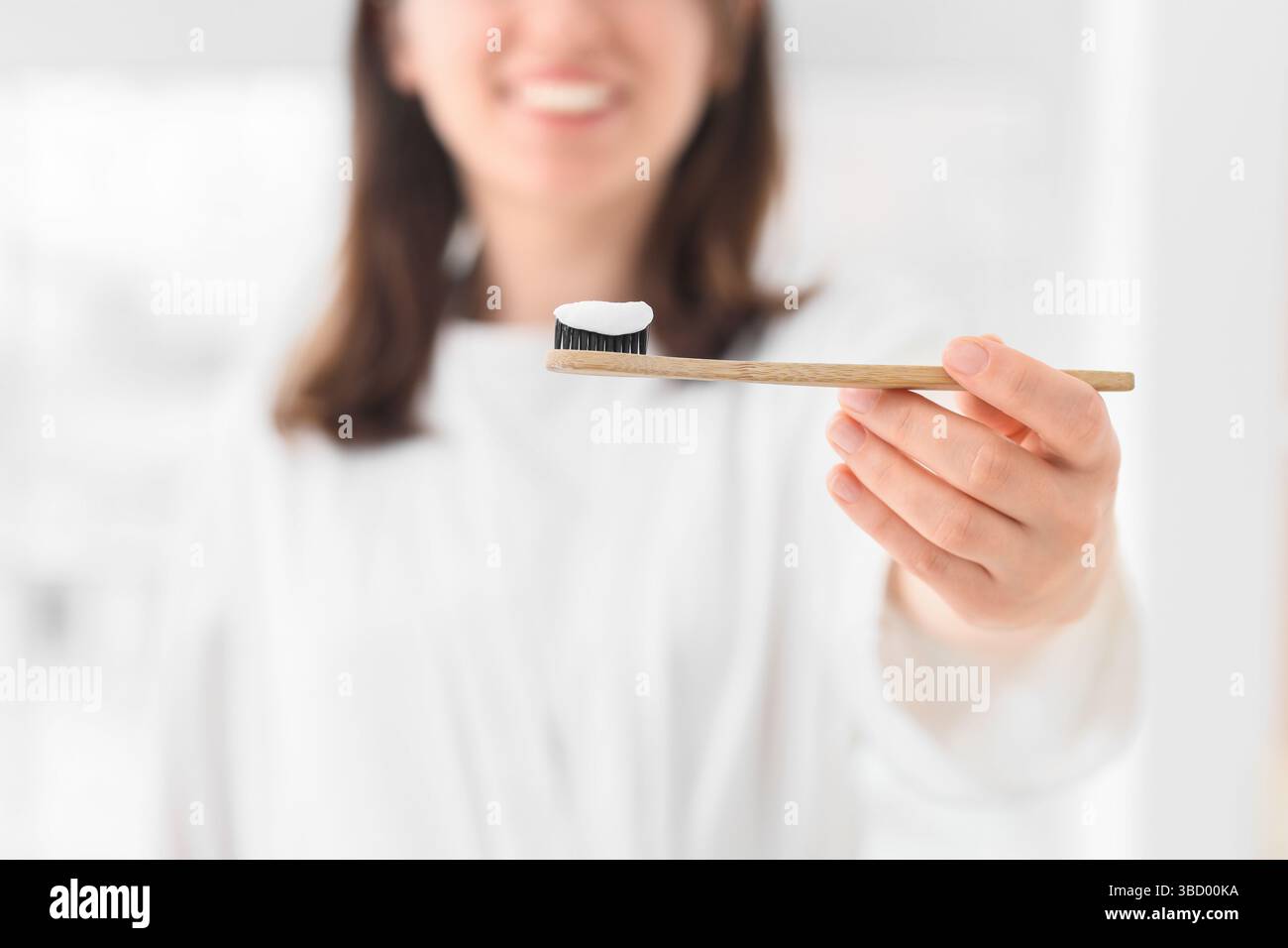 Woman with applied paste on bamboo tooth brush in bathroom, closeup Stock Photo