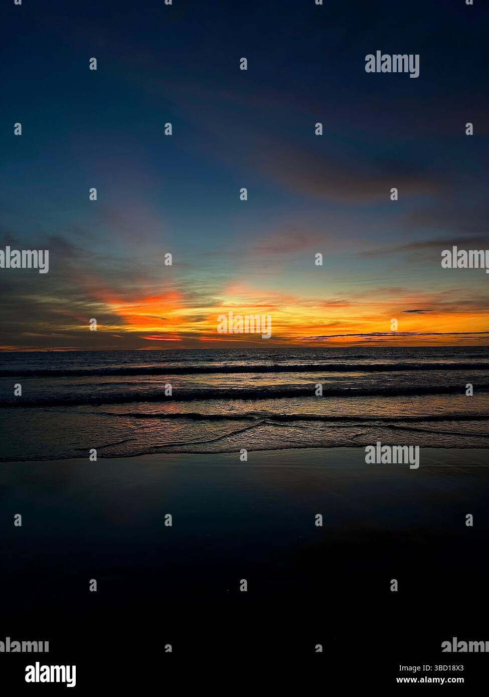 Colorful sunset over calm ocean waves with reflections on wet sand — a serene and inspiring coastal evening scene. - Smartphone Captured Stock Image