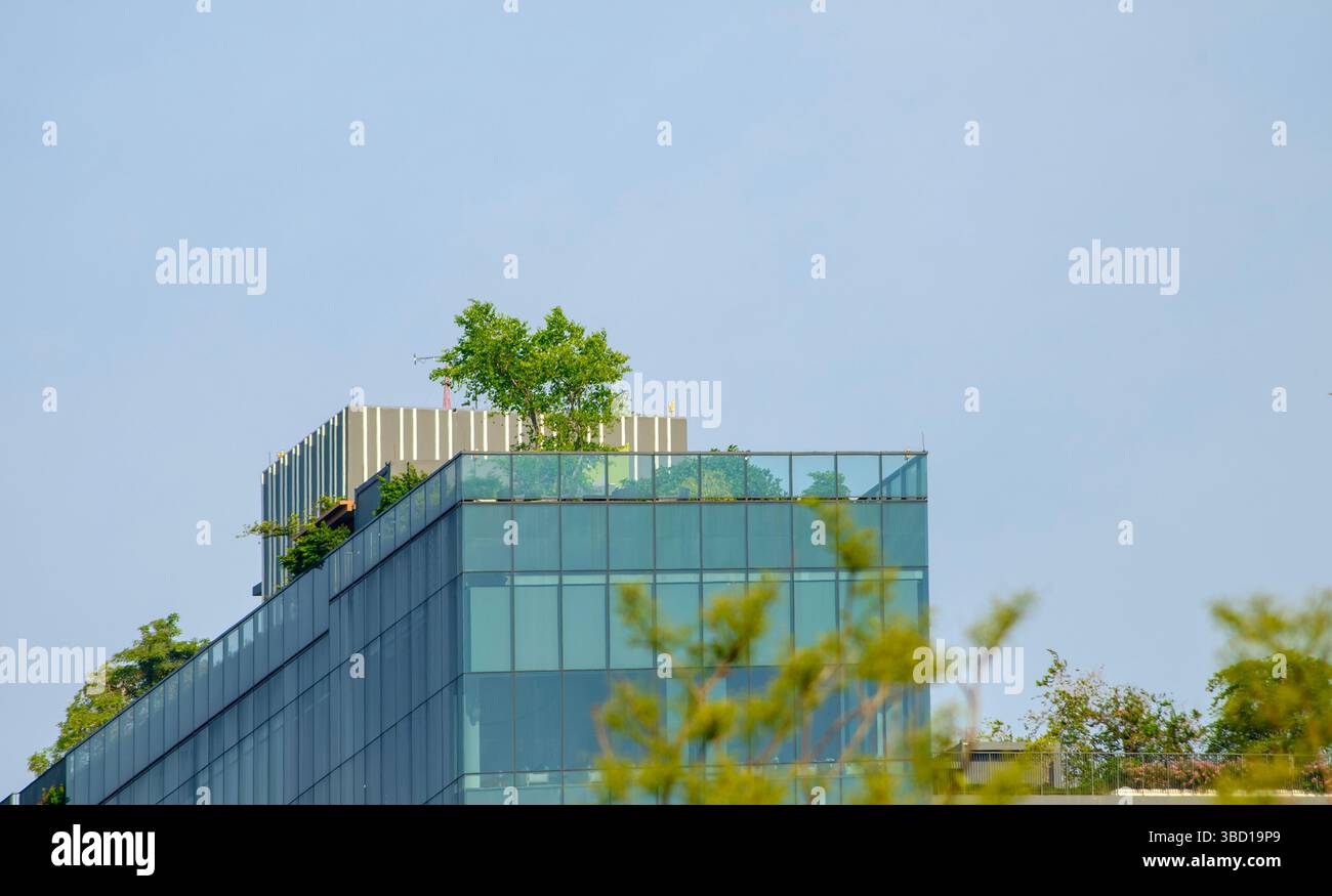 A contemporary glass building features a rooftop garden with lush green ...