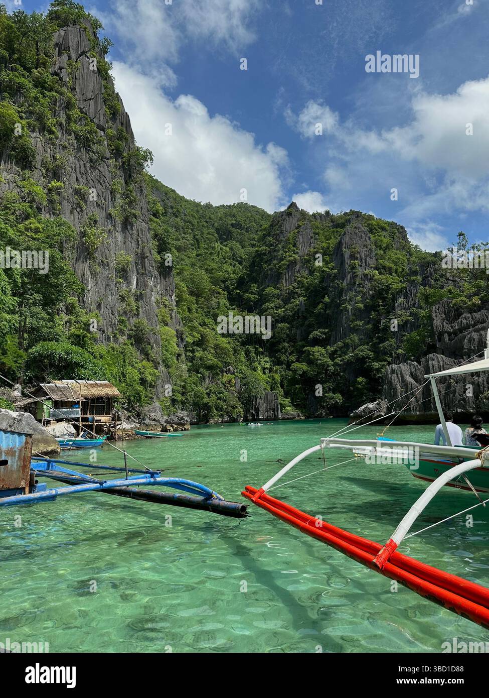 Traditional boats float on crystal-clear turquoise waters beside limestone cliffs and lush jungle—perfect for travel and eco-tourism themes - Smartphone Captured Stock Image