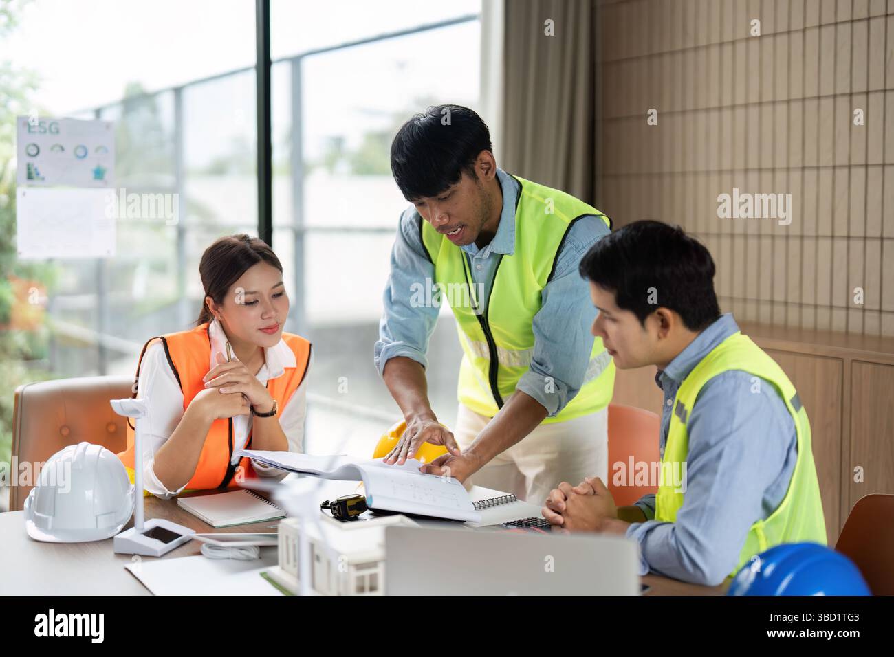 Green Tech Strategy Meeting. Engineers collaborating on sustainable projects in an eco-friendly workspace. Stock Photo