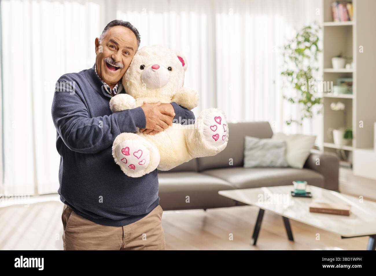 Happy mature man hugging a teddy bear in a living room Stock Photo - Alamy