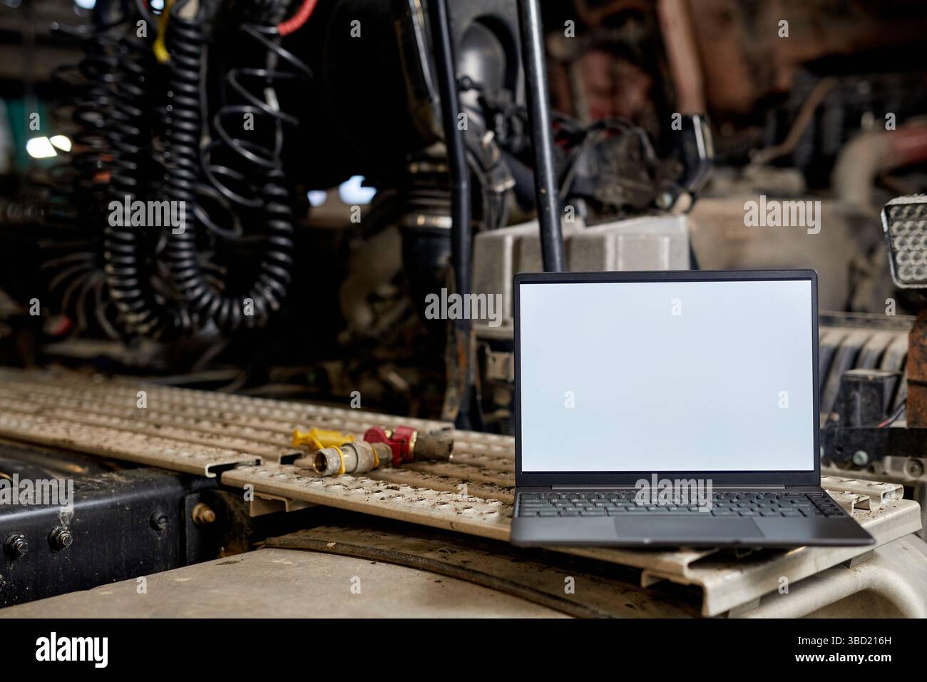 Open Laptop Displaying Blank Screen on Industrial Workbench Stock Photo