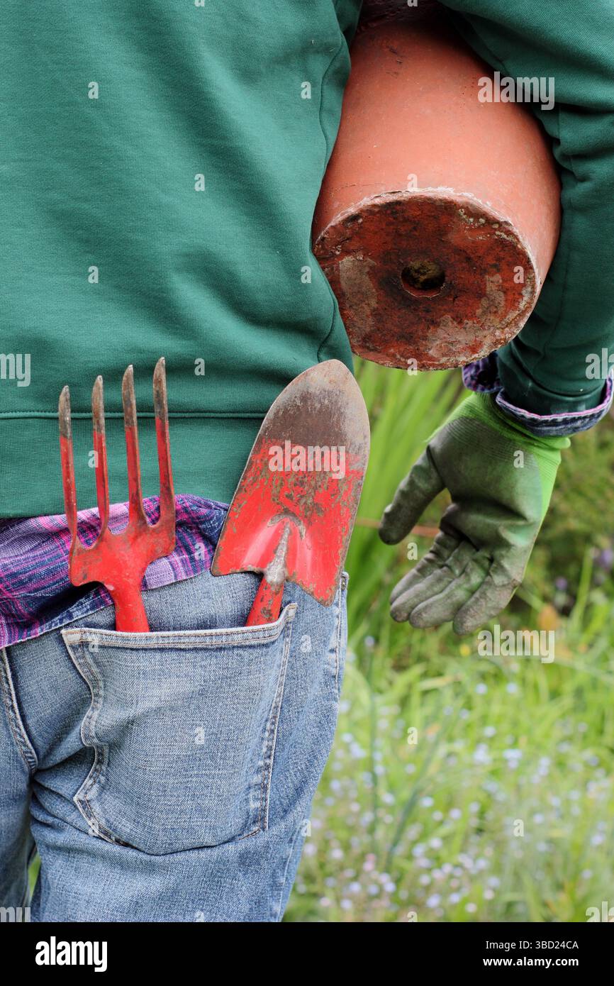 Gardening. Man with garden pot, vintage trowel and fork in a late spring garden. UK Stock Photo