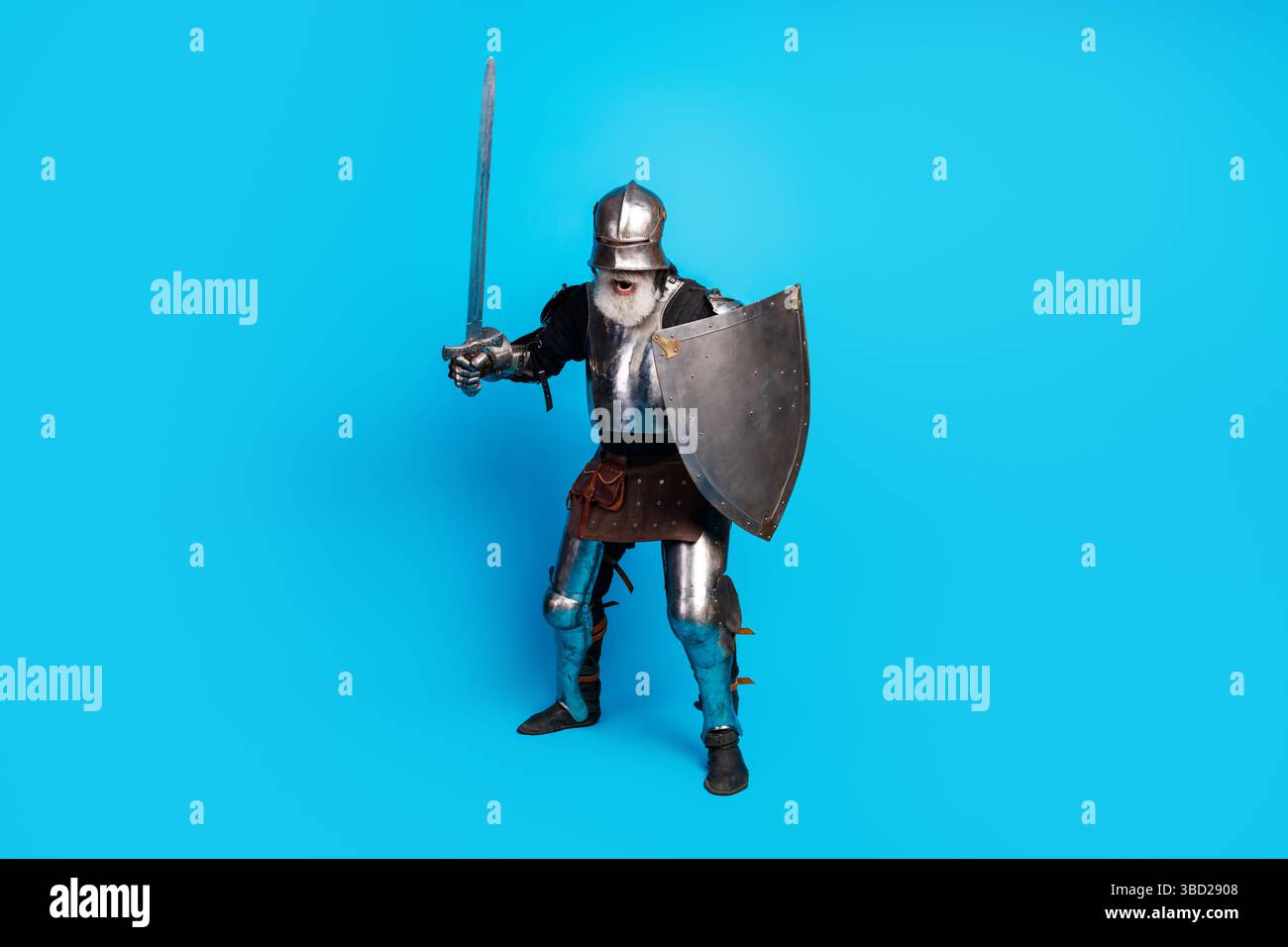 Medieval knight in full armor holding a sword and shield with a blue ...