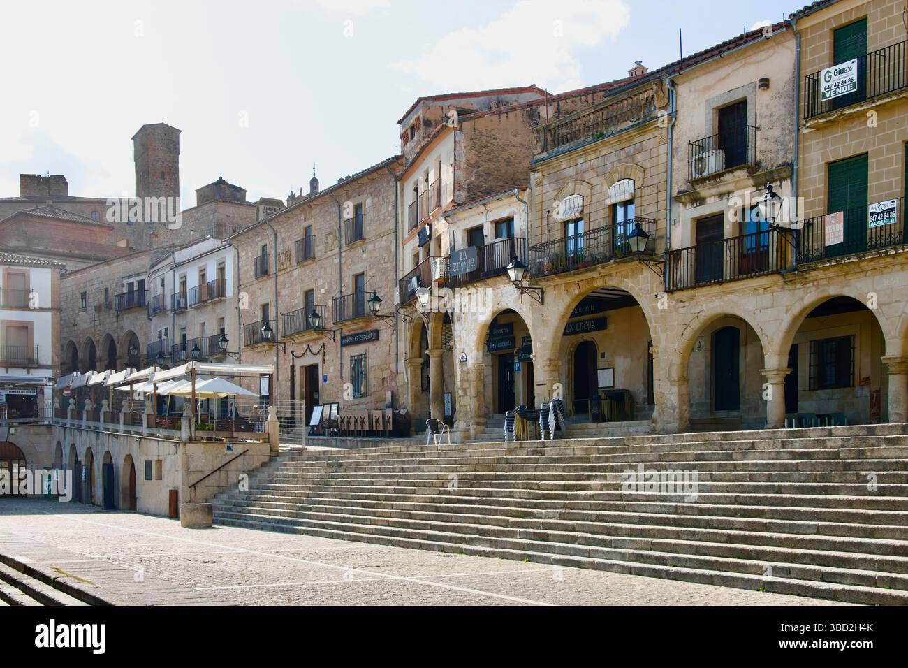 Steps up to an arcade with restaurant terraces and the tower of the palacio de Luis de Chaves Plaza Mayor Trujillo Caceres Extremadura Spain Europe Stock Photo