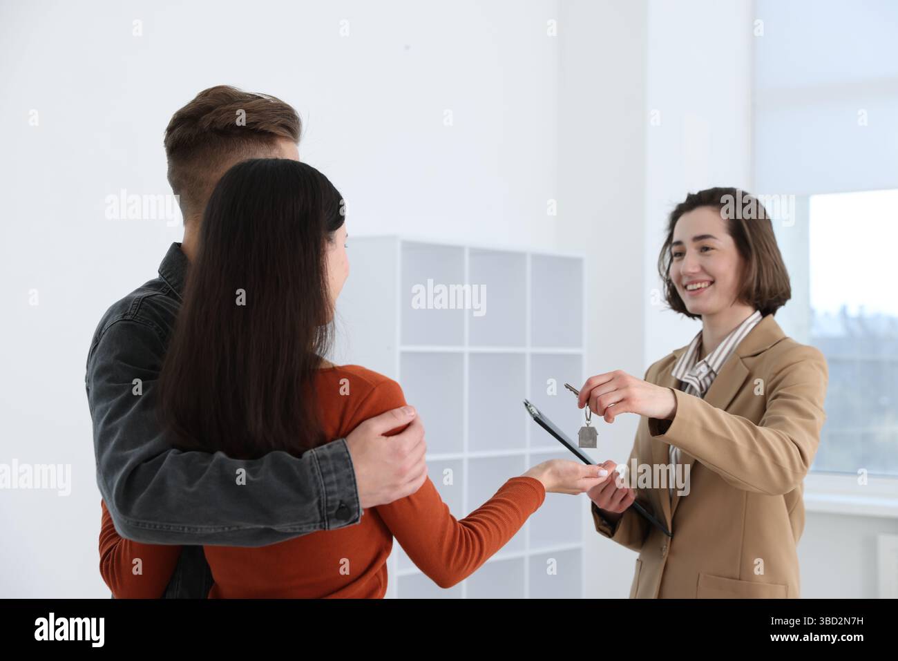 Real estate agent giving house key to new owners indoors Stock Photo ...