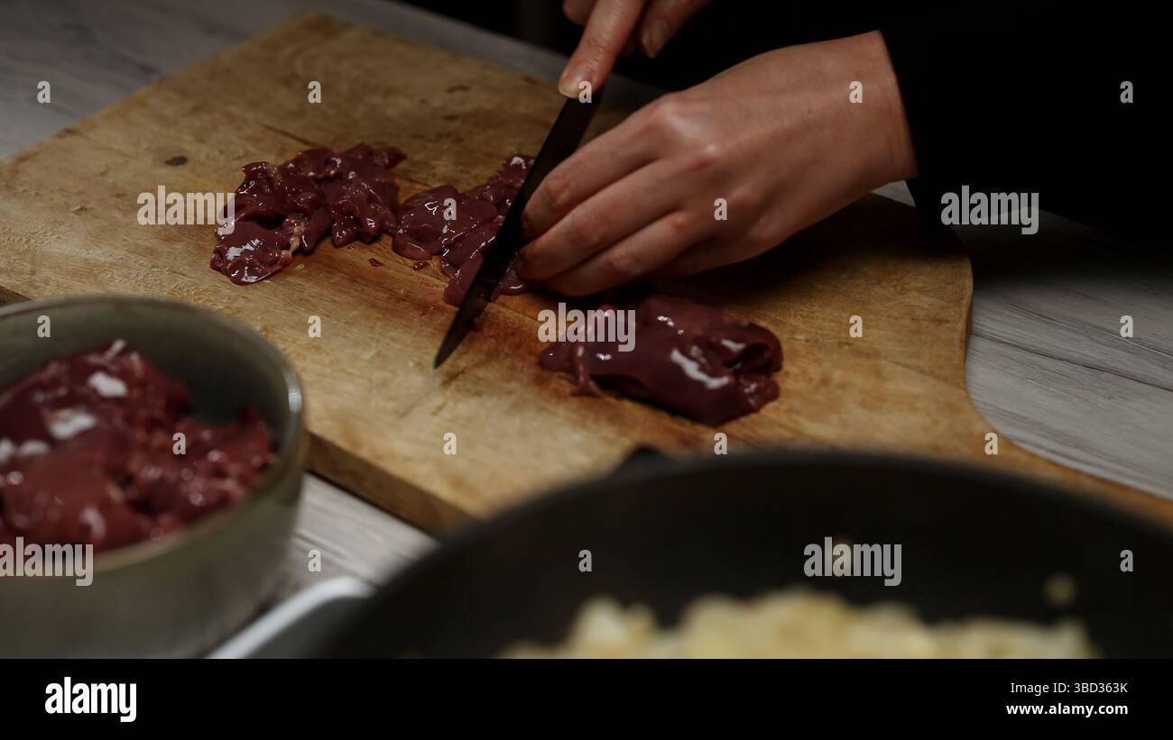 Chef Cutting Raw Chicken Liver on Wooden Board. Stock Photo