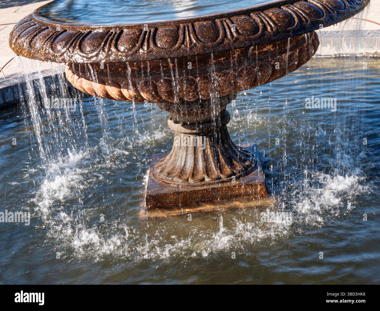WATER FOUNTAIN FEATURE Water flowing off an ornamental old weathered limestone garden feature water fountain in bright sunlit situation. RHS Wisley UK Stock Photo
