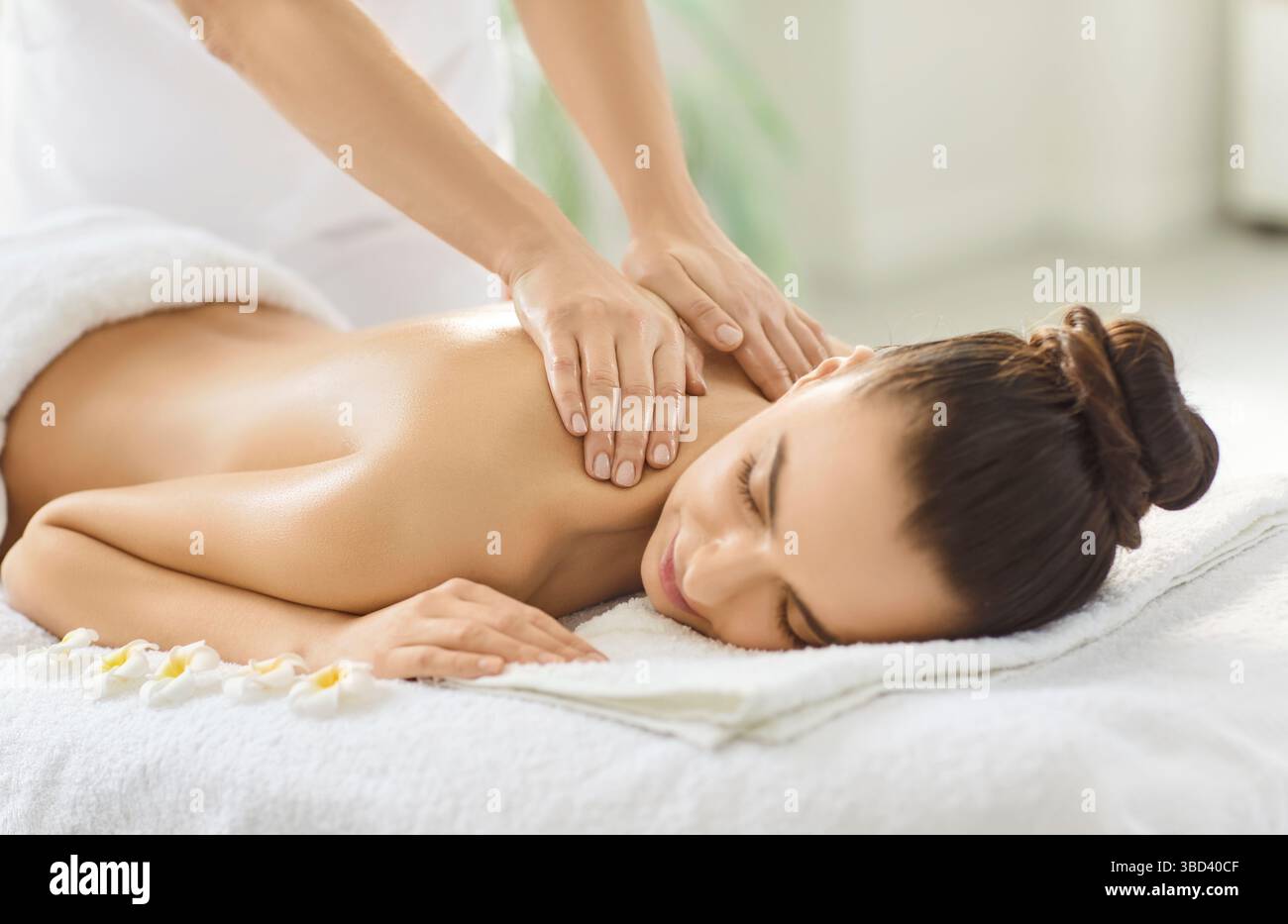 Cropped image of unknown massage therapist doing back massage for woman client Stock Photo