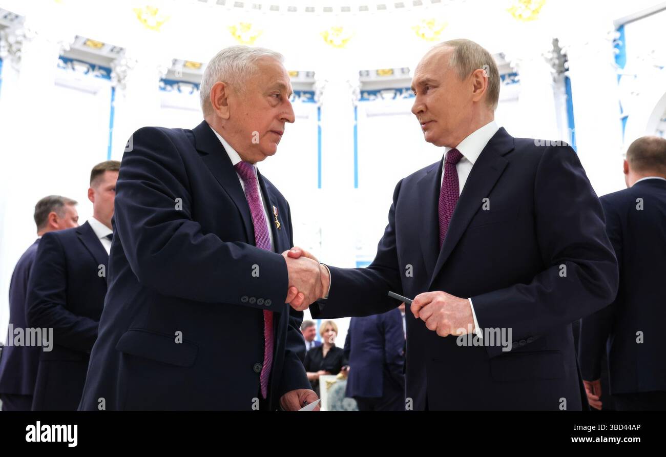 Moscow, Russia. 22nd May, 2025. Russian President Vladimir Putin, right, congratulates Nikolai Kharitonov, left, during a reception following a ceremony at the Catherine Hall of the Kremlin Senate Palace, May 22, 2025 in Moscow, Russia. Kharitonov, State Duma deputy and Chairman of the State Duma Committee for the Development of the Far East and the Arctic, received the title of Hero of Labour. Credit: Alexander Kazakov/Kremlin Pool/Alamy Live News Stock Photo