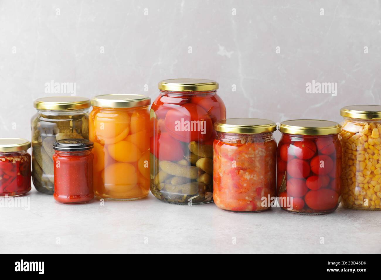 Many jars with different pickled products on light table Stock Photo