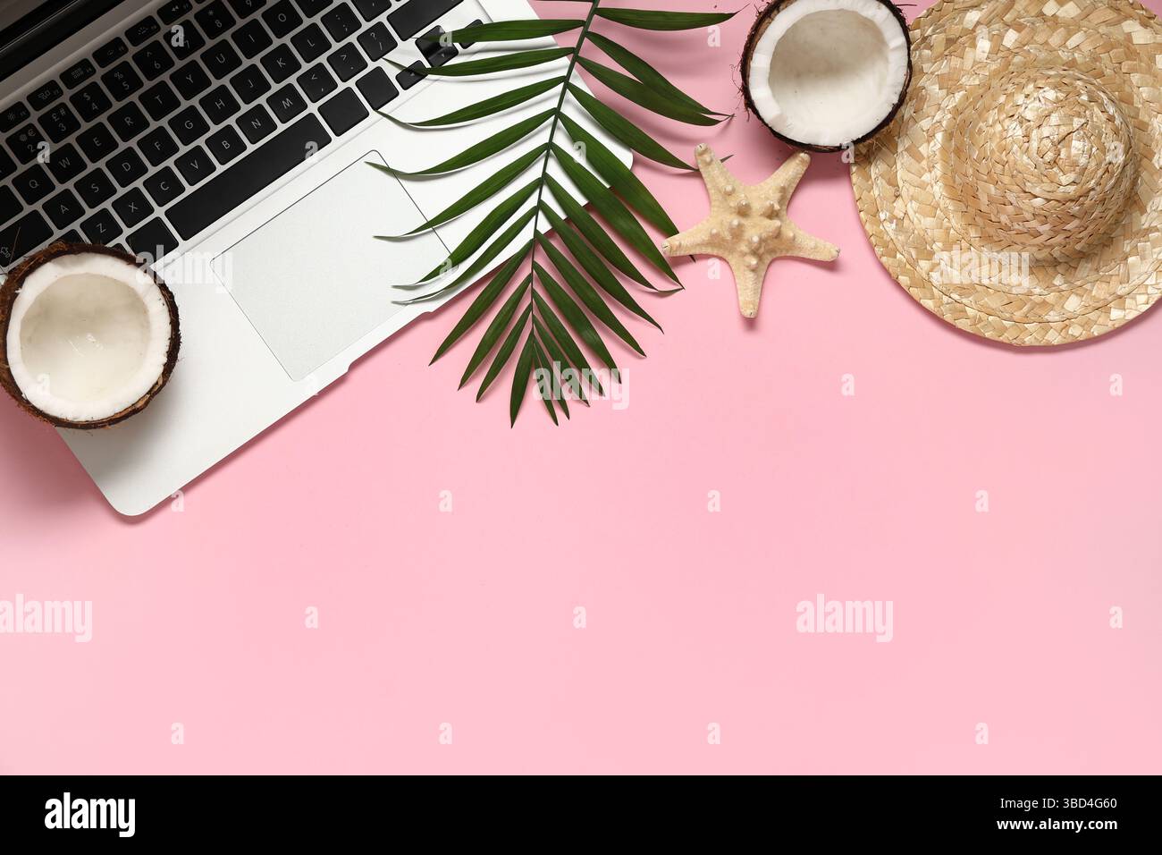 Laptop with palm leaf, hat and coconut on pink background Stock Photo