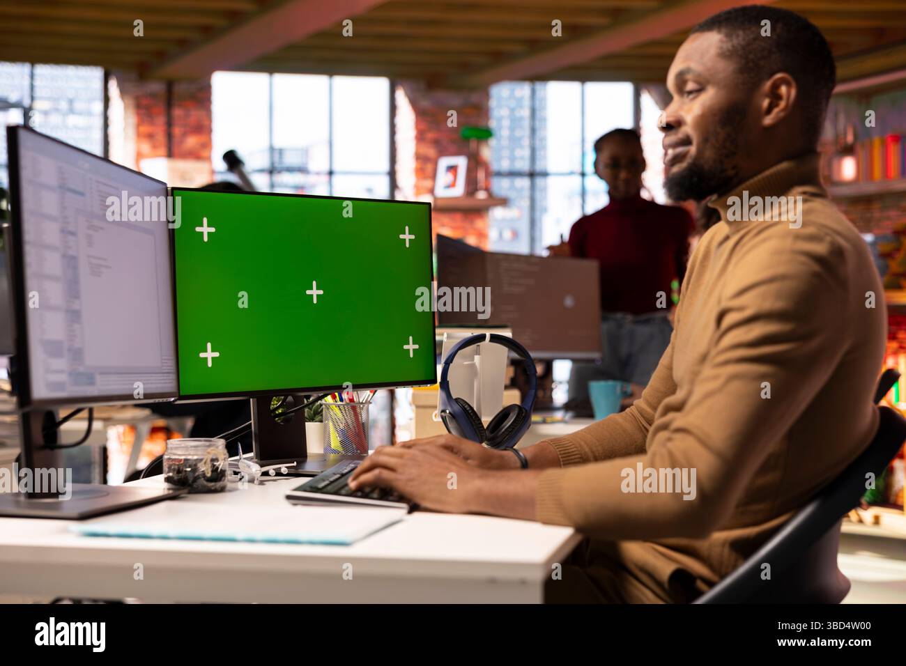 Smiling IT engineer using isolated screen PC in startup office and programming languages to build applications. Happy software development agency employee optimizing code on chroma key computer Stock Photo
