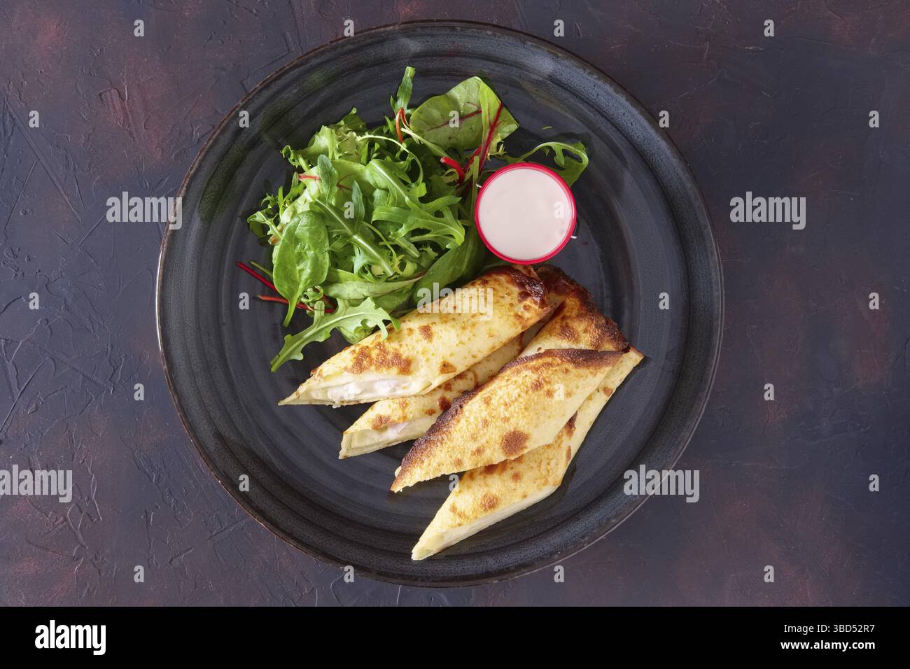 Thin pancakes stuffed with ham and melted cheese served with spinach, arugula, corn and chard salad Stock Photo