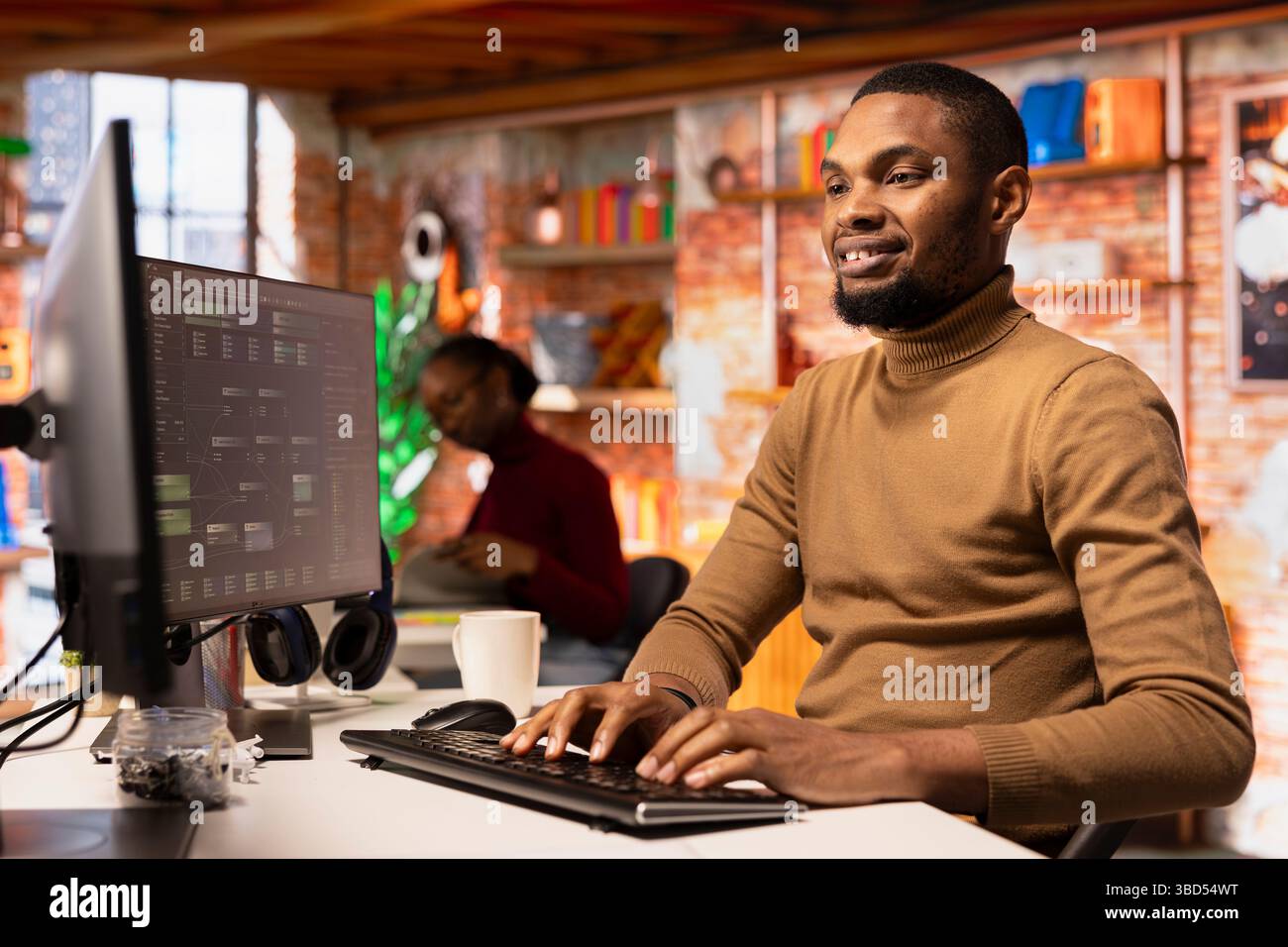 Upbeat IT engineer coding advanced AI algorithm in startup office, refining machine learning models to enhance automation. Cheerful man using coding platform in Silicon Valley workplace Stock Photo