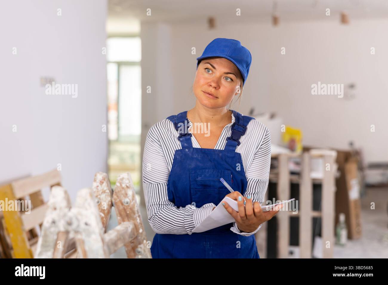 Female contractor taking notes while planning works at building site Stock Photo