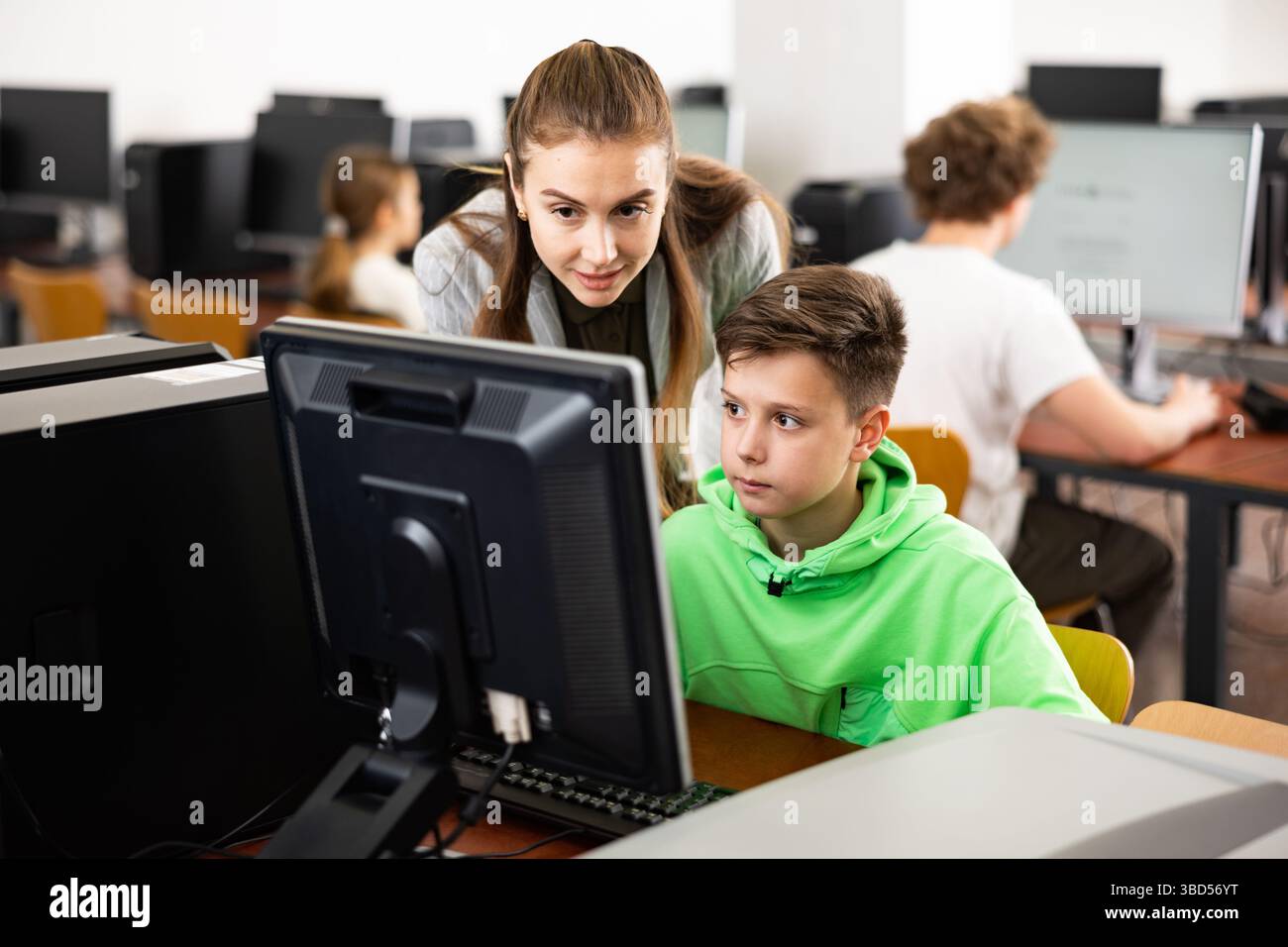 Female teacher consulting tween boy studying in computer class Stock Photo