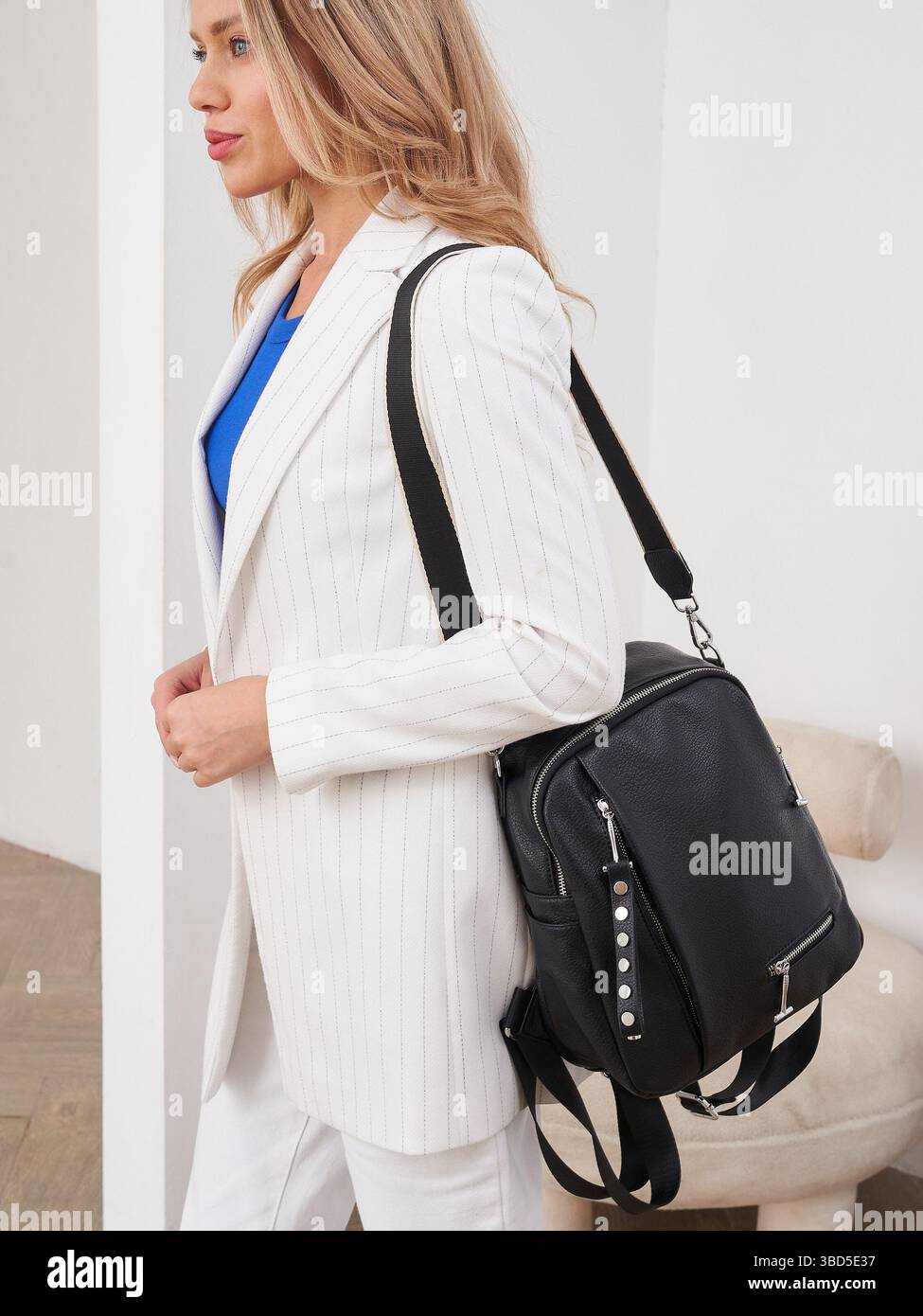 Blonde woman in white pinstripe blazer and blue top carries a stylish ...