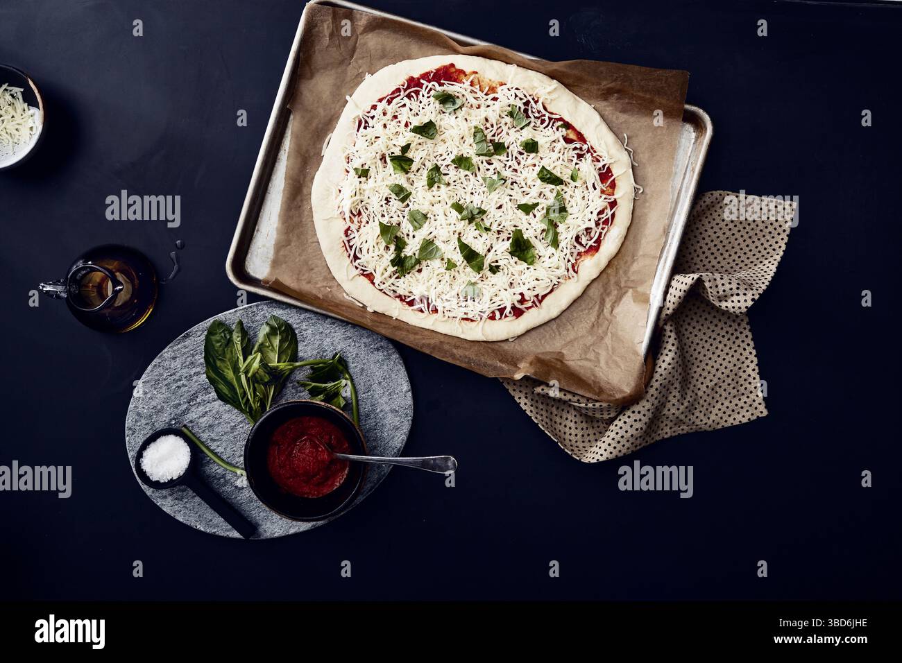 Person stretches dough on a dark surface dusted with flour. Stock Photo
