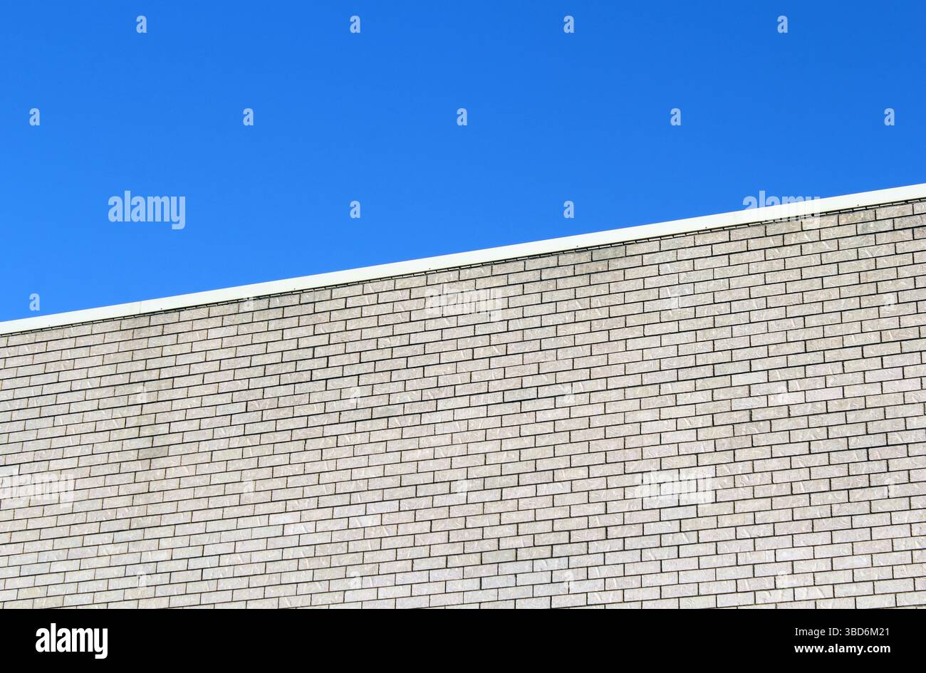 Light-colored brick wall of a building against a blue sky background textured abstract Stock Photo