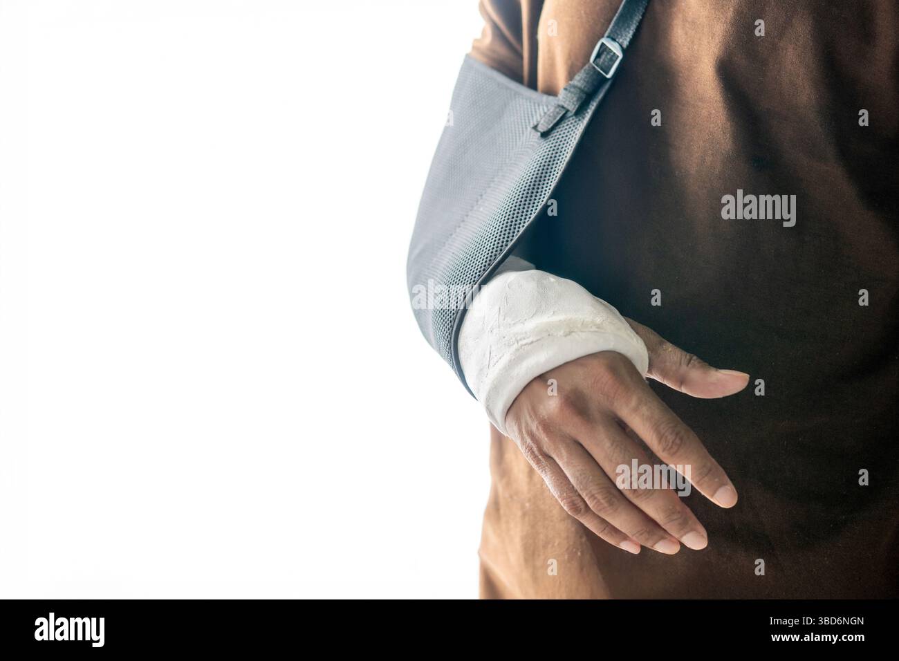 A close-up shot of a person wearing a black arm sling and a hand cast isolated on white background. Stock Photo