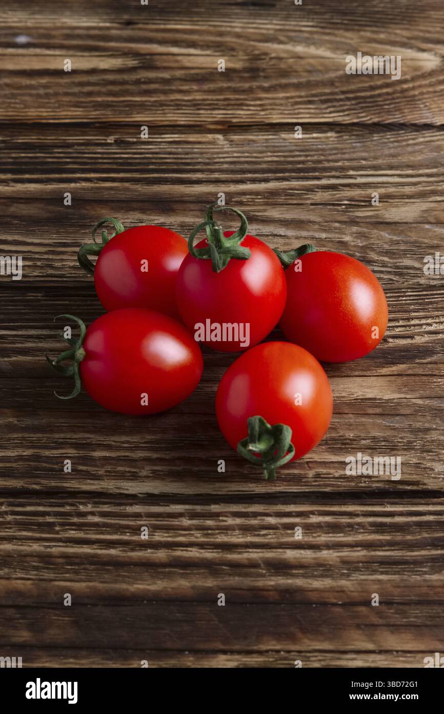 Five fresh cherry tomatoes on wooden table Stock Photo