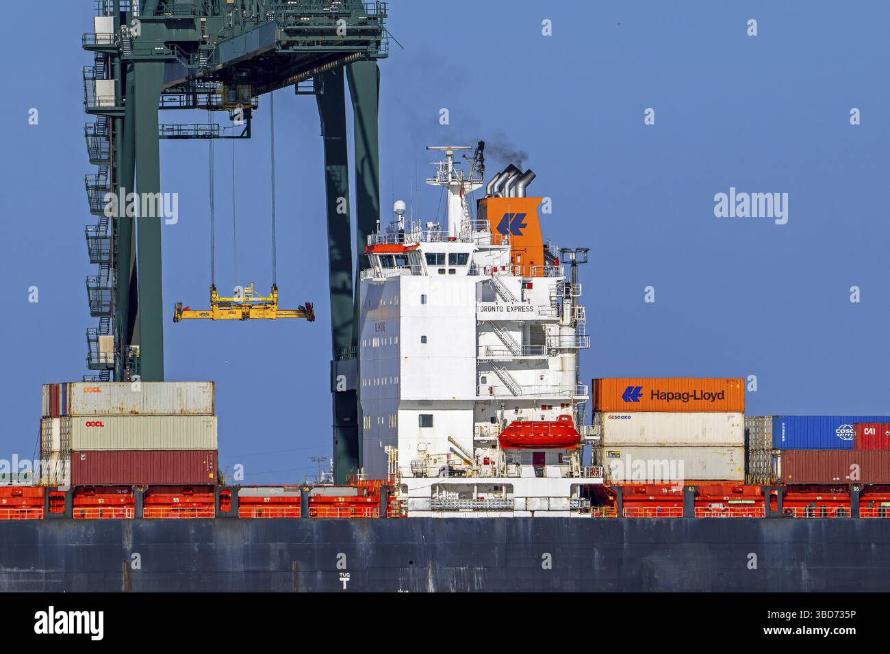 Gantry crane and stacked containers on container ship docked at ...