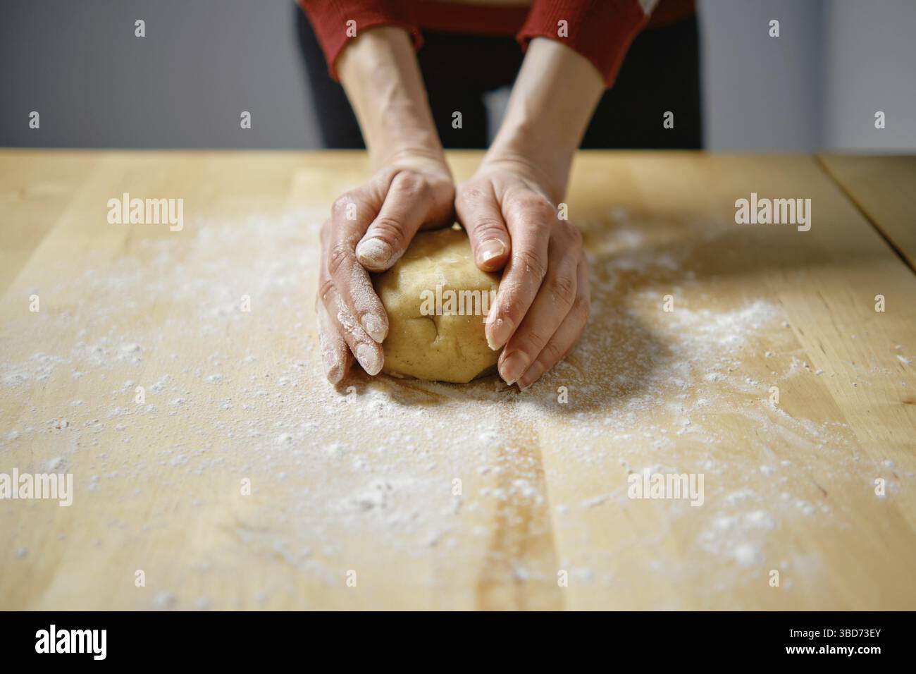 Unrecognizable woman kneads dough with her hands on the table Stock Photo