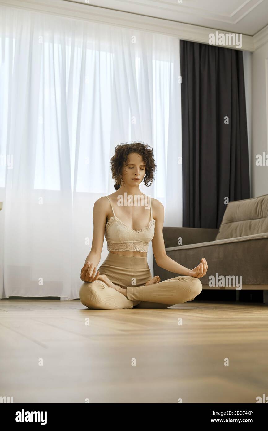 Meditative woman sits in lotus position at home Stock Photo