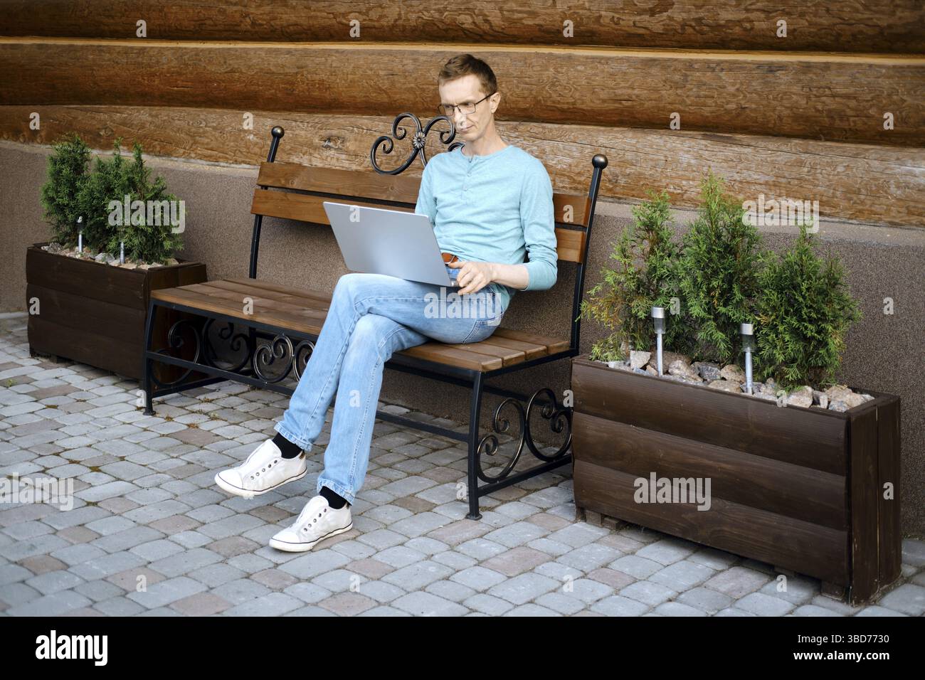 Middle aged man makes online order using laptop outdoors Stock Photo