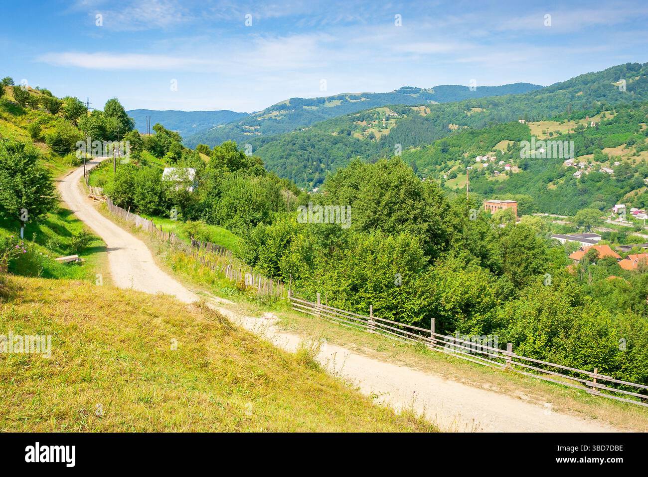 rural landscape with road in summer. countryside nature with mountain in background. rustic scenery with green grass on hill and blue sky. scenic view Stock Photo