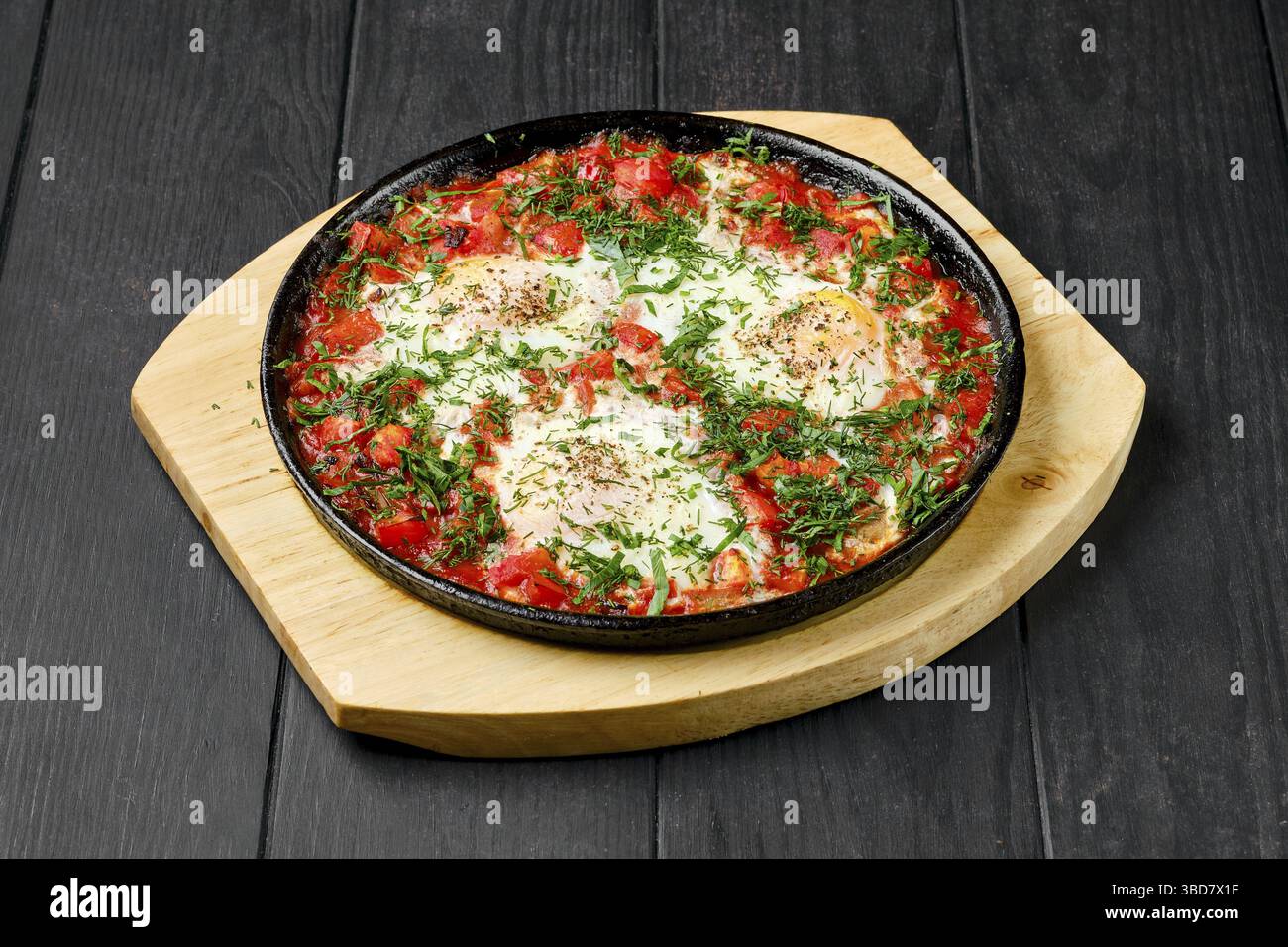 Eggs fried with ham and tomato in cast iron skillet Stock Photo