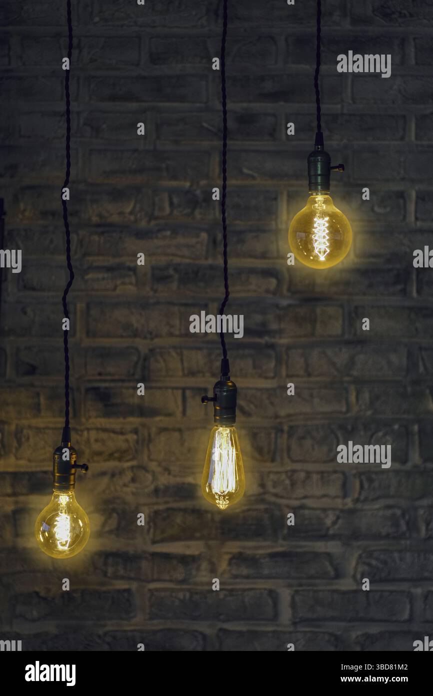 Vintage edison light bulbs on wire with brick wall on background Stock Photo