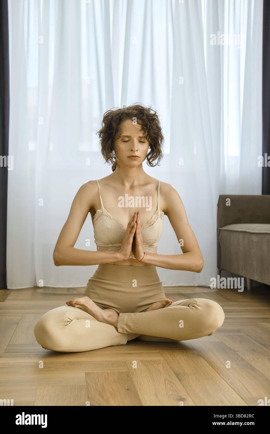 Meditative woman sits in lotus position at home Stock Photo
