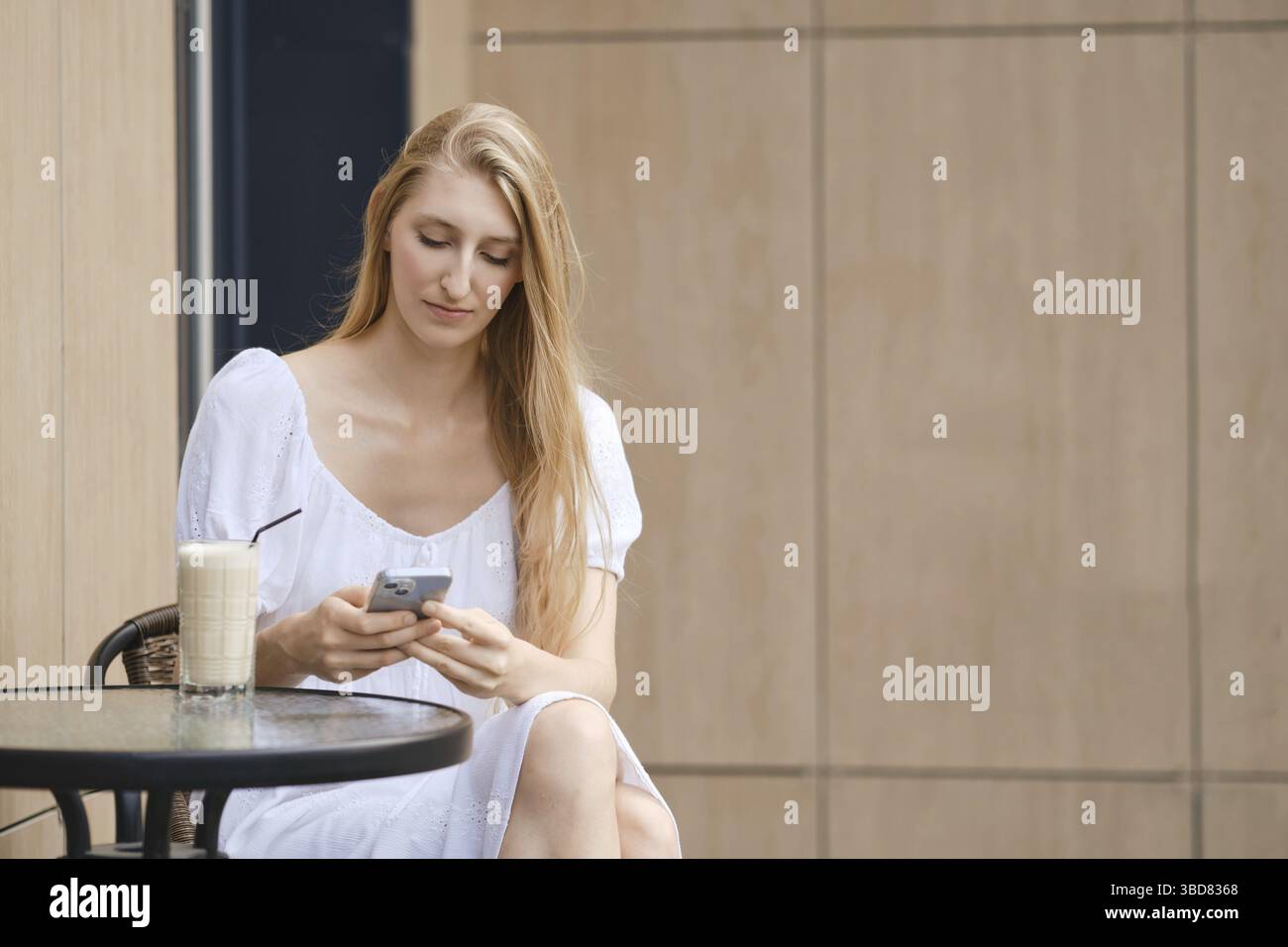 Young woman using smartphone while having coffee break outdoor Stock Photo