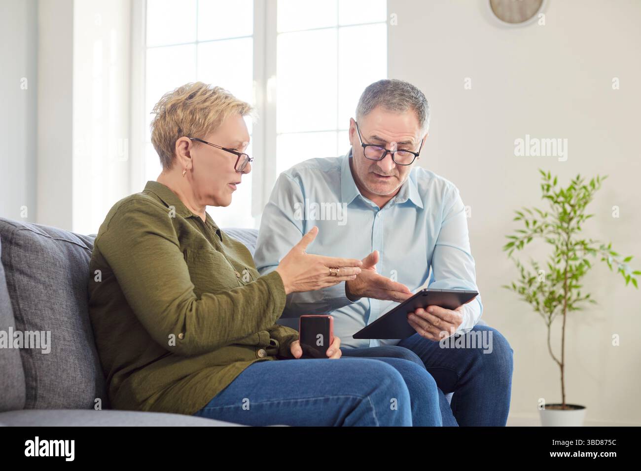 Focused Senior Couple Using Tablet Pc At Home For Online Activities Stock Photo