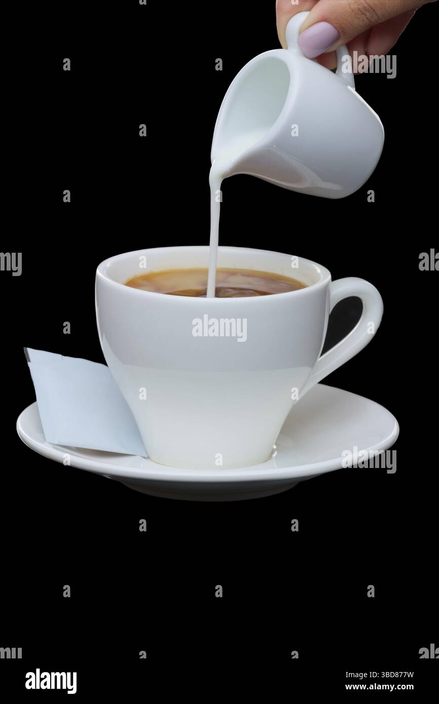 Pouring milk in coffee. Photo with clipping path isolated on black background Stock Photo