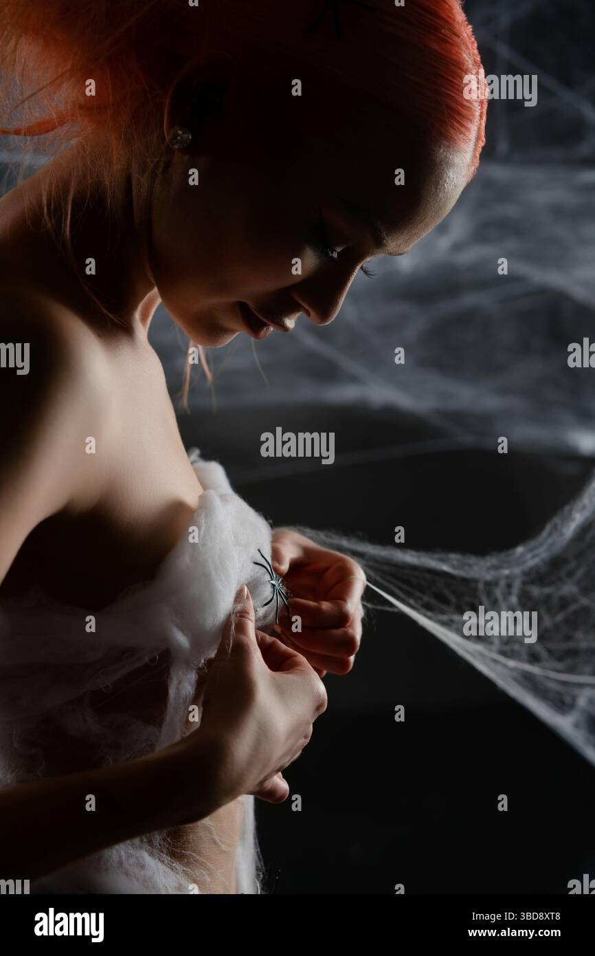 Red-haired woman trapped in a net, revealing her beauty amid the web Stock Photo