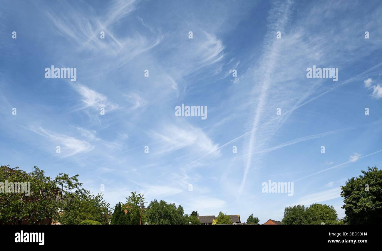 Cirrus clouds and contrails in a blue summer sky in the UK Stock Photo