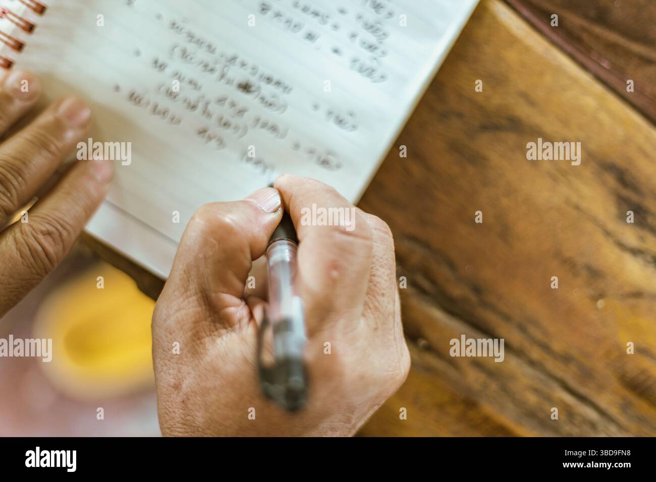 A hand writing on a notebook on a table, selective focus Stock Photo