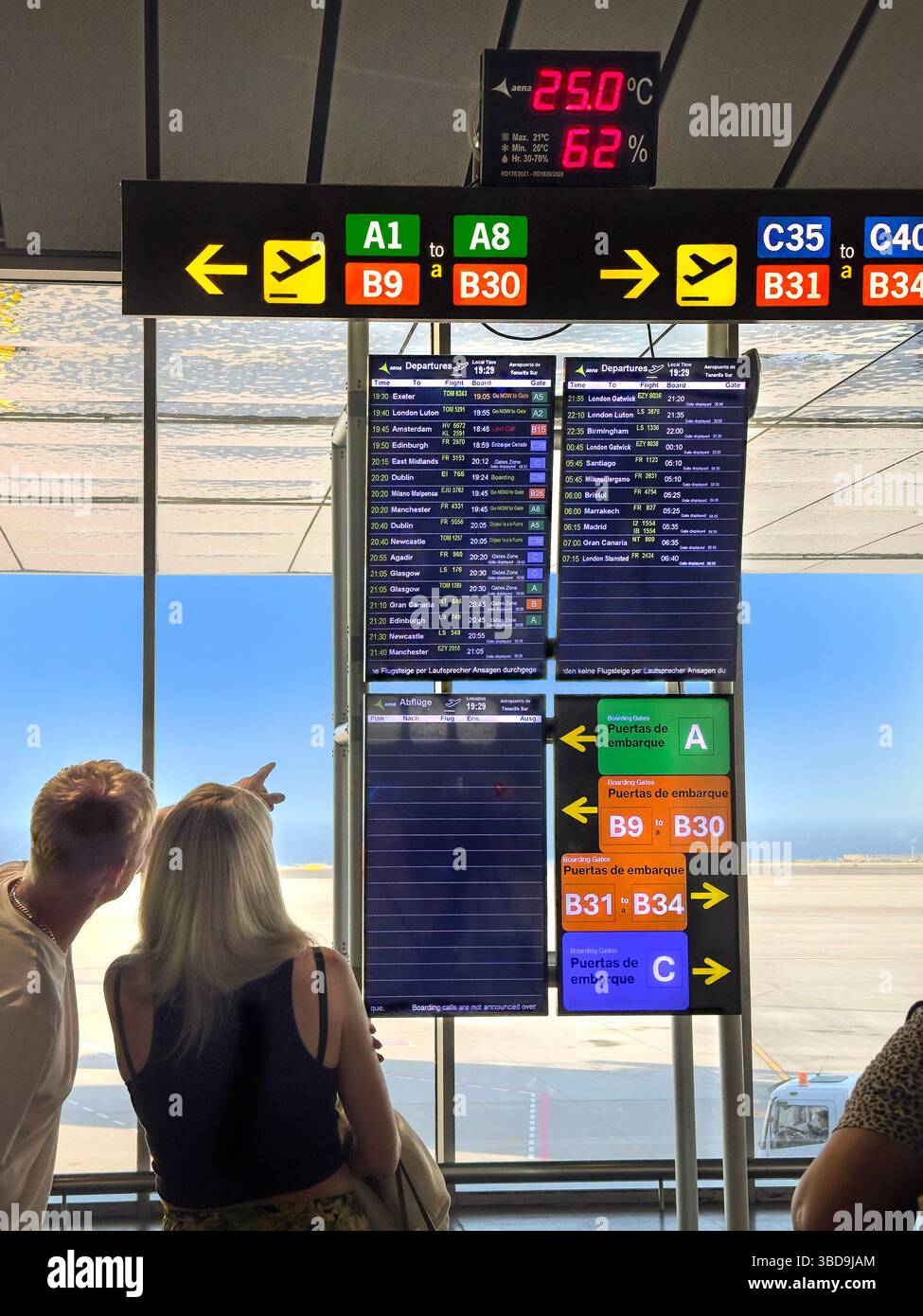 two passengers terminals  direction sign & departure times board  hanging from ceiling in the terminal at Tenerife sur  airport - Smartphone Captured Stock Image