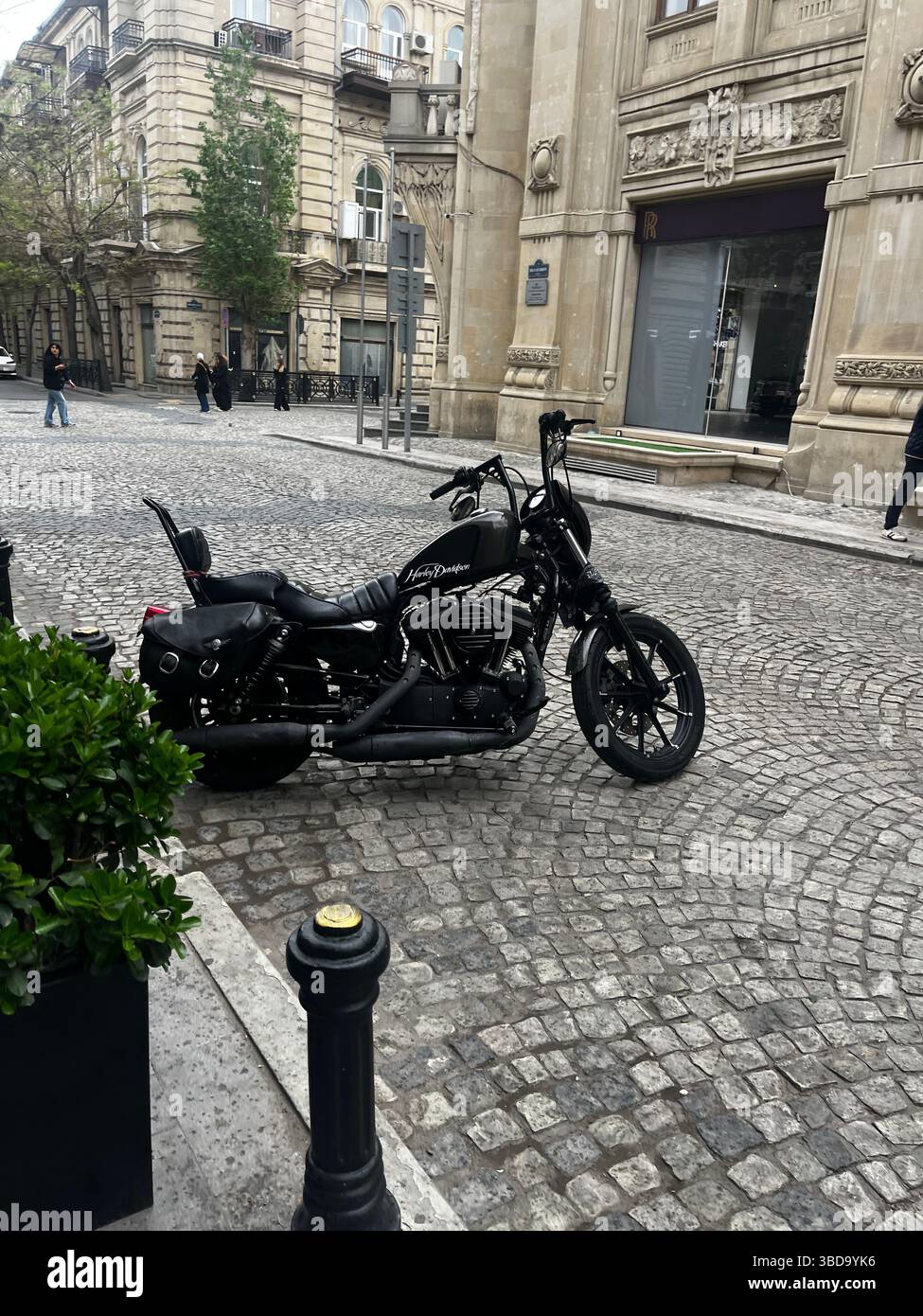 A sleek black motorcycle parked on a cobblestone street, surrounded by elegant historic buildings, blending modern style with classic architecture - Smartphone Captured Stock Image