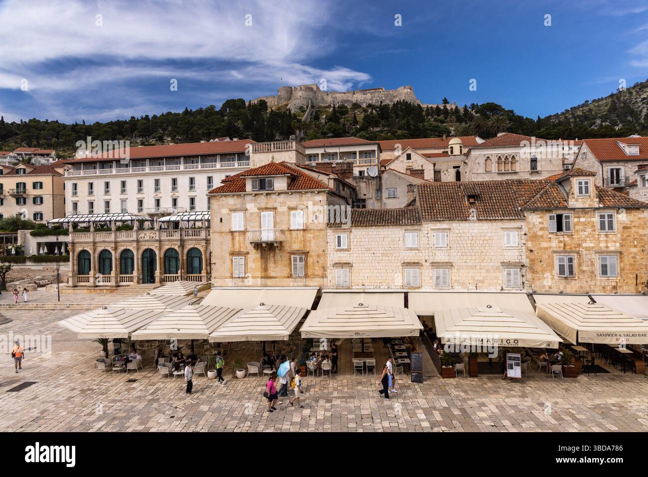 St Stephens Square the main square with restaurants cafes and bars and  Španjola fortress in the background, Hvar town, Croatia, Europe Stock Photo