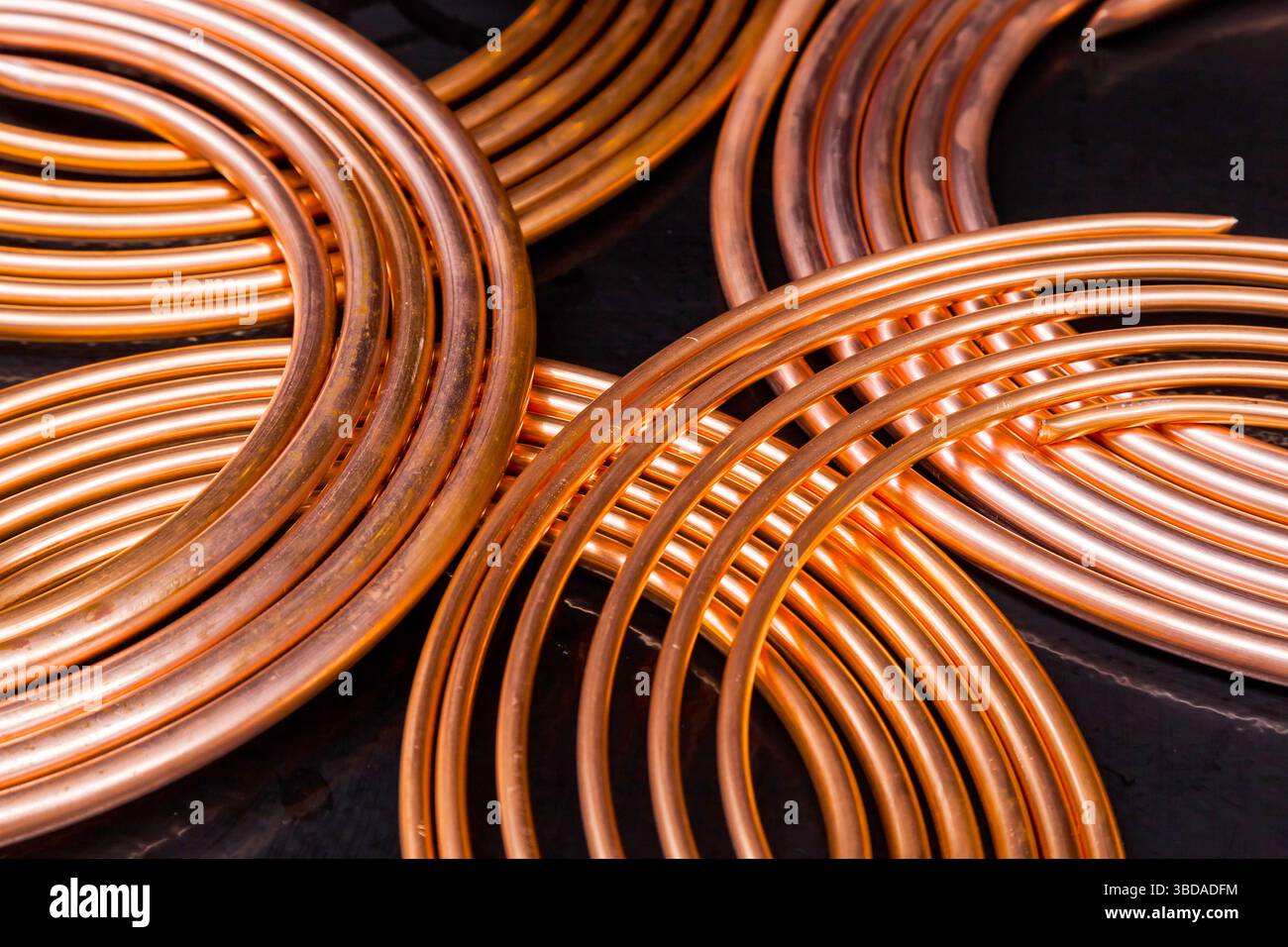 Twisted new copper tubes on a black background Stock Photo - Alamy