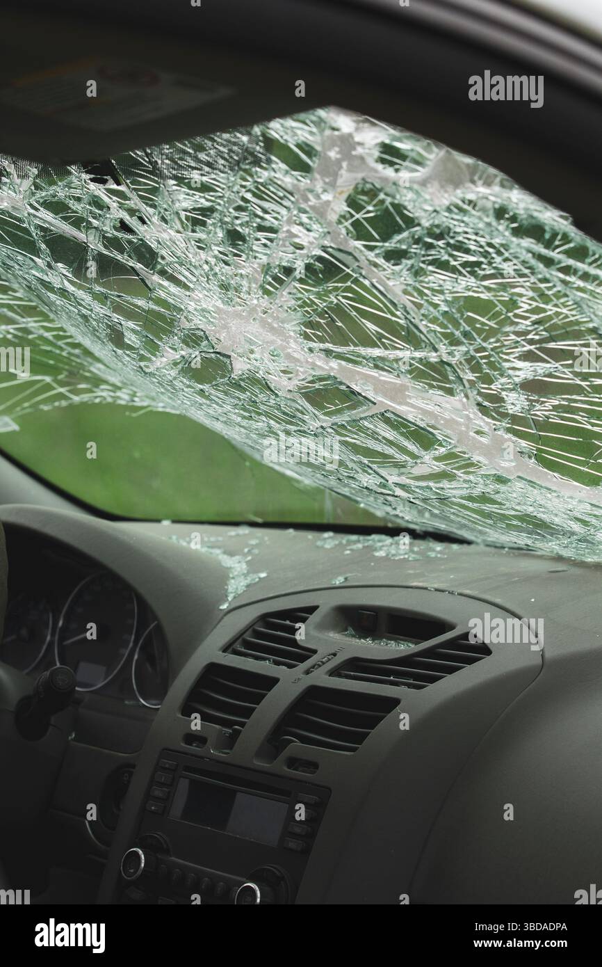 Interior view of car with shattered windshield and broken glass on dashboard. Impact damage visible across safety glass. Stock Photo