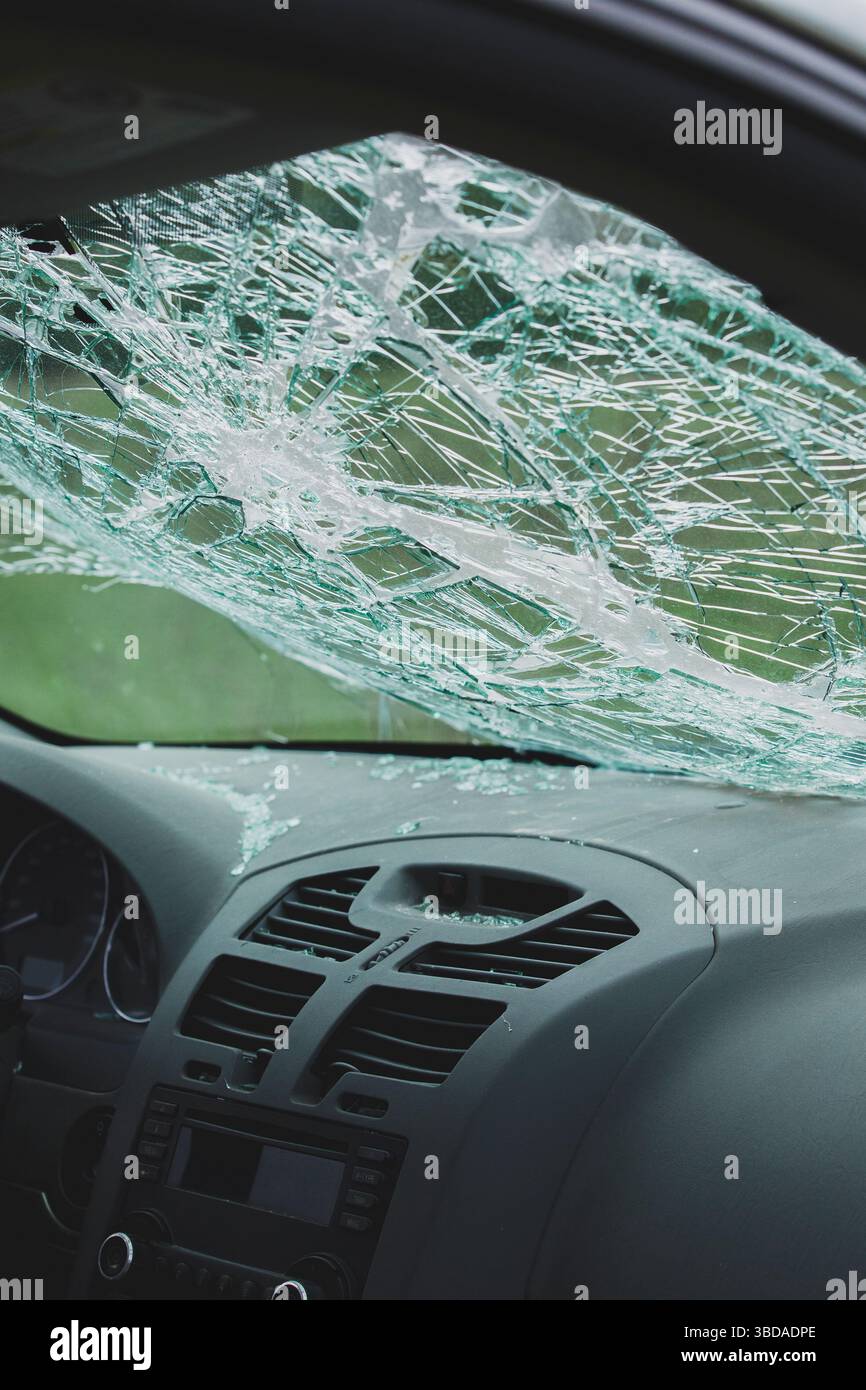 Interior view of car with shattered windshield and broken glass on dashboard. Impact damage visible across safety glass. Stock Photo
