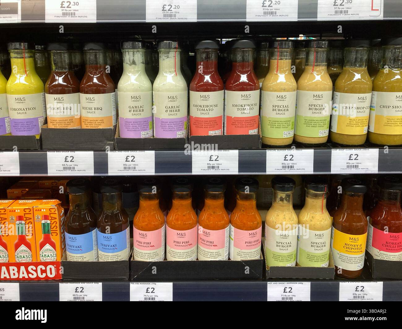 Choice of various bottles of sauces, condiments and dressings for sale on Marks & Spencer shelves, UK - Smartphone Captured Stock Image