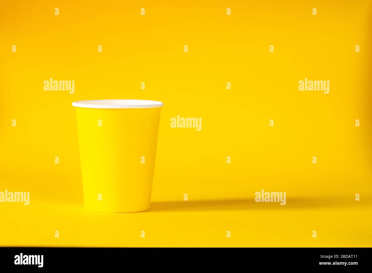 Yellow paper cup on yellow background. copy space Stock Photo
