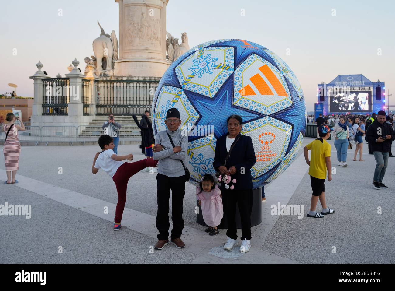 People pose for pictures by a giant football at Lisbon's riverside ...